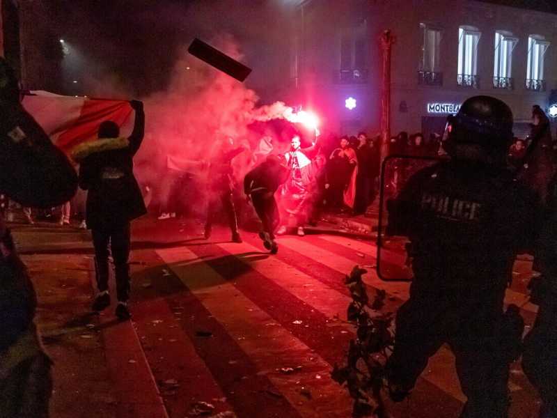 I tifosi della Francia e del Marocco festeggiano a Parigi le rispettive vittorie ai Mondiali, sotto gli occhi della polizia (Ansa)