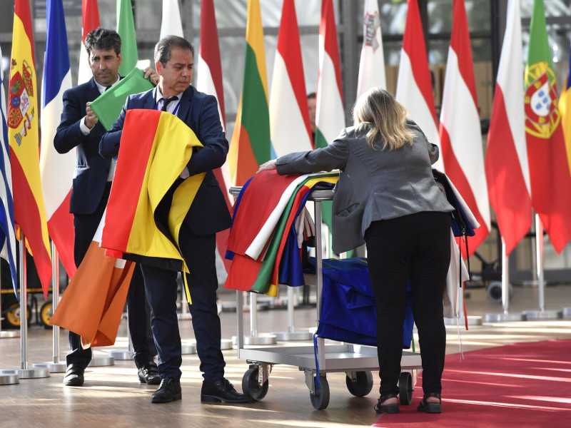 Membri del protocollo issano le bandiere degli stati membri dell'Ue prima di un vertice a Bruxelles (Foto AP/Geert Vanden Wijngaert)&nbsp;<br />