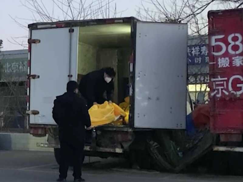 Lavoratori caricano sacchi per i cadaveri su un camion in un complesso funerario a Pechino, venerdì 16 dicembre 2022 (AP Photo/Dake Kang) <br />