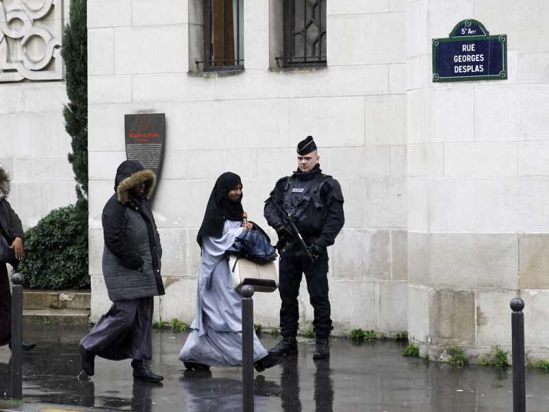 Un ufficiale di polizia francese mentre alcune donne musulmane lasciano la Grande Moschea di Parigi (Thierry Chesnot/Getty Images) <br />