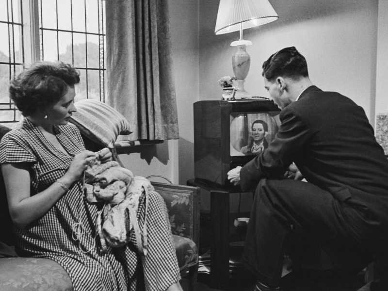 Una donna incinta lavora a maglia mentre il marito sintonizza uno schermo tv, Regno Unito, 1956 (Grace Robertson/Getty Images) <br />