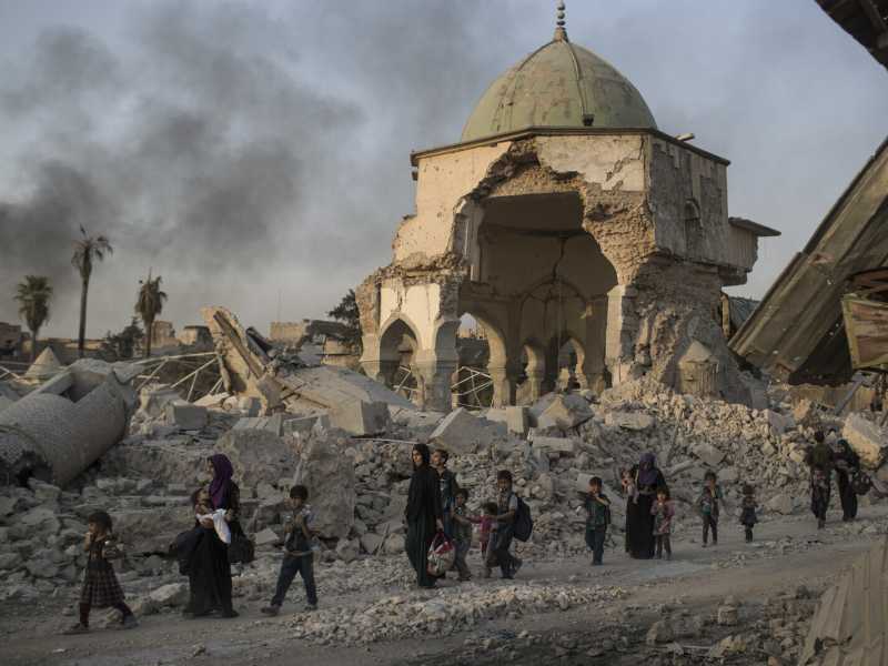 Mosul, luglio 2017: civili iracheni in fuga nei pressi di una moschea distrutta durante il conflitto con lo Stato islamico (foto Felipe Dana/Ap) <br />