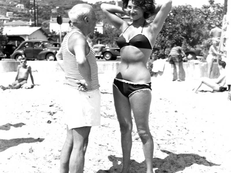 Pablo Picasso fa sorridere una giovane donna sulla spiaggia di Golfe Juan sulla Costa Azzurra francese negli anni '60. (Getty Images)&nbsp;<br />