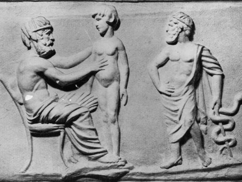 Un bassorilievo greco di un medico che esamina un paziente mentre Ippocrate osserva con in mano il simbolo della medicina, circa 350 a.C. (Hulton Archive/Getty Images)&nbsp;<br />
