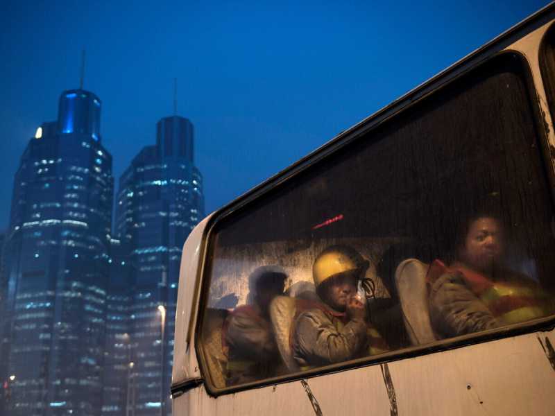 Lavoratori cinesi aspettano in un autobus dopo il loro turno in un cantiere edile a Pechino (Foto di Kevin Frayer/Getty Images) <br />