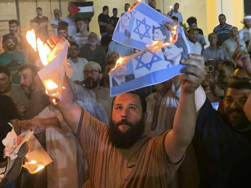 A Tripoli un manifestante brucia la bandiera di Israele (foto LaPresse)