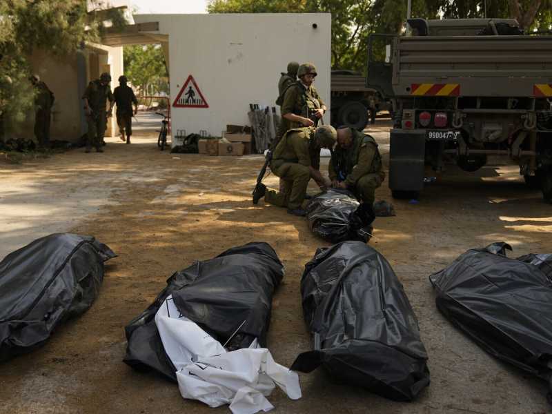 Soldati accanto ai corpi degli israeliani uccisi dai militanti di Hamas nel kibbutz Kfar Azza marted&igrave; 10 ottobre 2023 (AP Photo/Ohad Zwigenberg)&nbsp;<br />