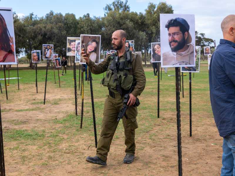 Un soldato cammina tra le foto delle vittime del festival musicale Noval sul luogo del massacro del 7 ottobre vicino al Kibbutz Re'im (Spencer Platt/Getty Images) <br />