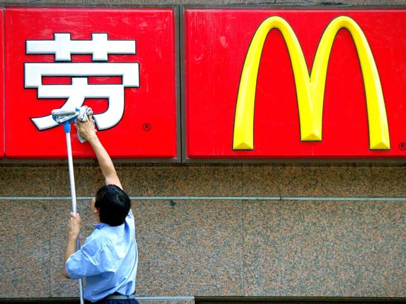 Un operaio cinese pulisce l'insegna di un ristorante McDonald's il 29 agosto 2001 a Pechino (Foto di Kevin Lee/Getty Images)&nbsp;<br />