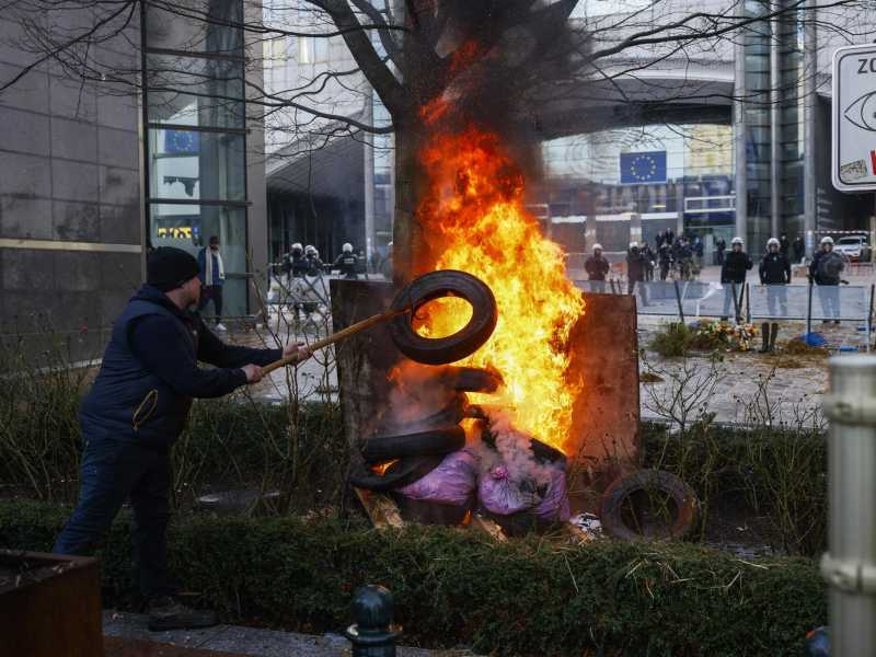 &nbsp;Un manifestante brucia dei rifiuti davanti alle istituzioni europee a Bruxelles - foto Ansa