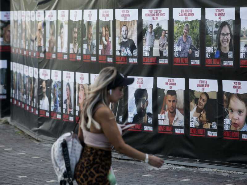 Una donna cammina accanto a manifesti con foto degli ostaggi israeliani nelle mani di Hamas. Hadera, Israele (Amir Levy/Getty Images)