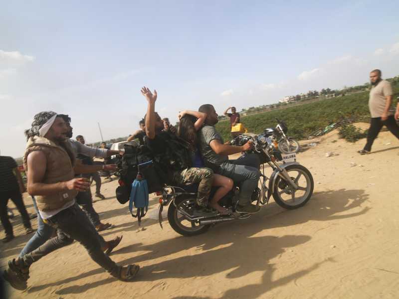 Alcuni militanti di Hamas trasportano un civile israeliano catturato nel kibbutz di Kfar Azza/ Ansa 