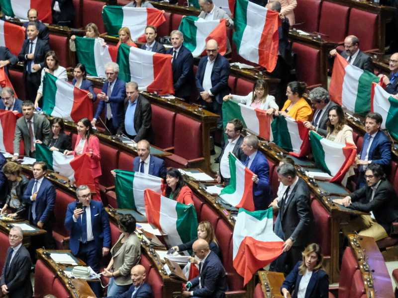 I deputati dell’opposizione protestano contro la riforma dell’autonomia differenziata sventolando il tricolore in Aula (foto LaPresse) <br />