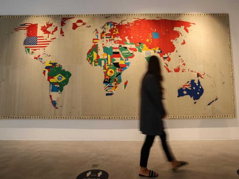 Una donna cammina davanti a un'opera della famosa serie di mappe ricamate di Boetti, nella galleria Sotheby's Dubai nel 2022 (Ansa) <br />