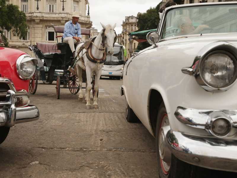 Auto americane d'epoca e una carrozza trainata da cavalli fuori da alcuni degli hotel pi&ugrave; costosi dell'Avana Vecchia (Foto di Chip Somodevilla/Getty Images)&nbsp;<br />