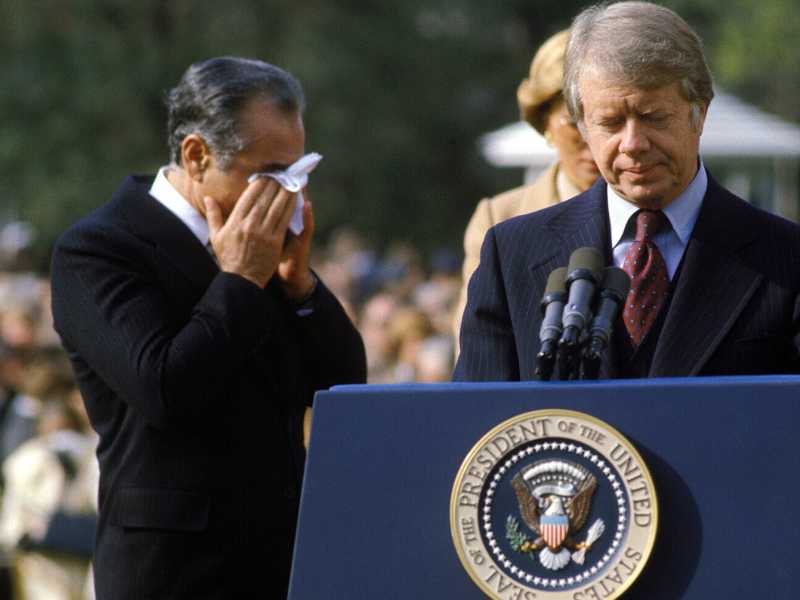 Il presidente Carter e lo shah Reza Pahlavi che si asciuga gli occhi per i fumi del gas usati in una manifestazione fuori dalla Casa Bianca (GettyImages)&nbsp;<br />