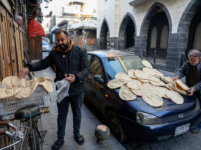 A Damasco due uomini stendono il pane appena sfornato (foto Getty)