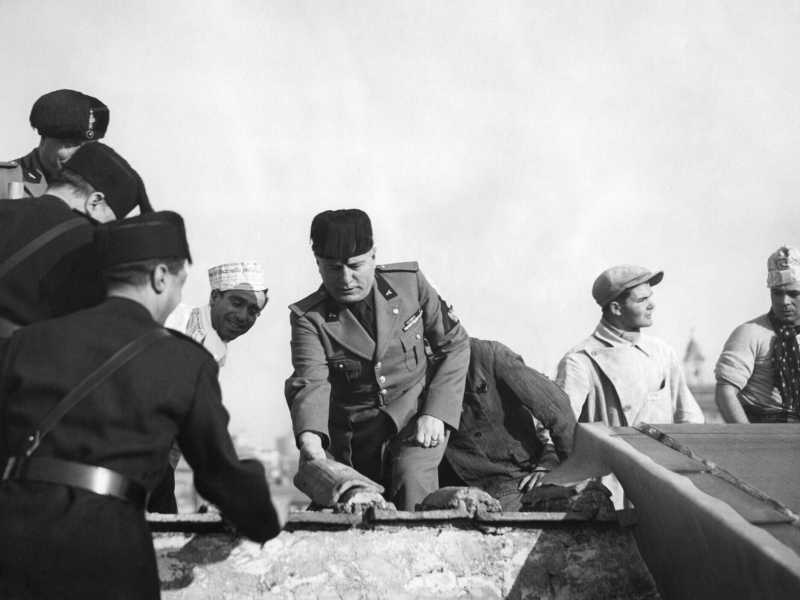 Benito Mussolini posa una piastrella all'inizio della costruzione di un nuovo edificio a Roma, il 19 febbraio 1935 (Gamma-Rapho via Getty Images)&nbsp;<br />