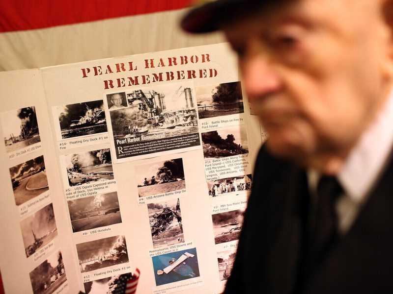 Il cappellano della USS Hornet, John Berger, accanto a un manifesto commemorativo di Pearl Harbor (Justin Sullivan/Getty Images) <br />
