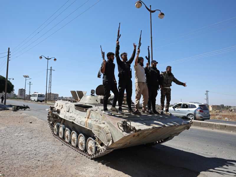Le forze governative esultano in piedi su un carro armato a Suwayda (foto Getty)