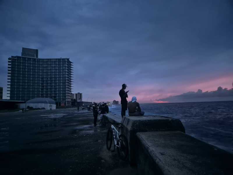 L'Avana: persone in piedi sulla riva davanti agli edifici spenti (Foto di Nick Kaiser/picture alliance)&nbsp;<br />