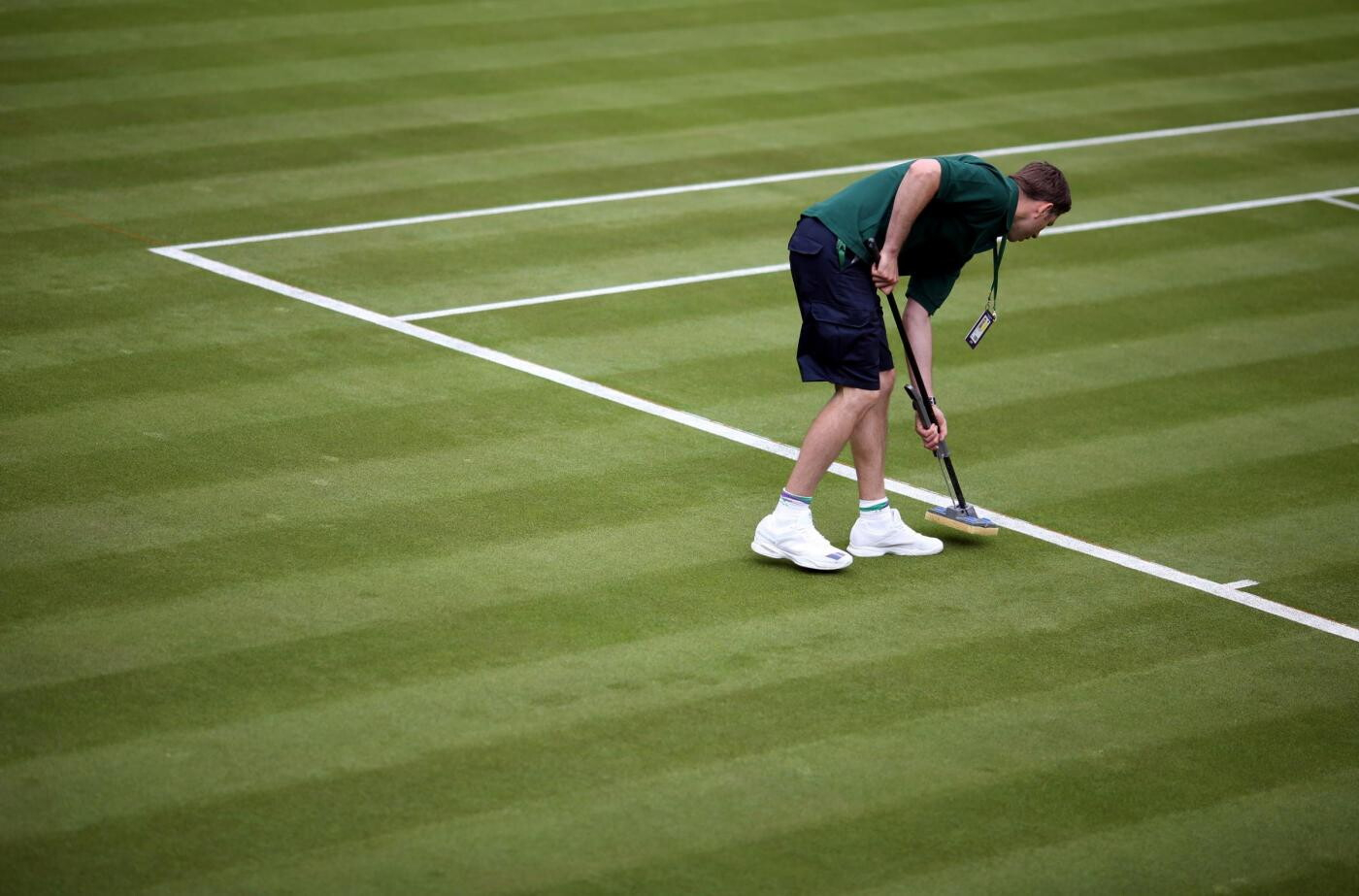 Un membro del "ground staff" segna con estrema precisione le linee del campo: sono dipinte di gesso bianco, per cui quando la palla in velocit&agrave; rimbalza sulla linea si alza quella che in gergo viene chiamata " la nuvoletta di gesso " che aiuta a capire se la palla &egrave; buona o no