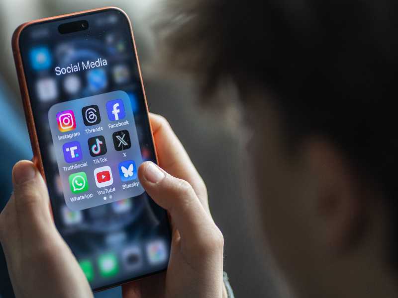 BATH, UNITED KINGDOM - MARCH 29: In this photo illustration a 14-year-old boy holds an iPhone screen displaying various social media and messaging apps on March 29, 2026 in Bath, England. On top row left to right, the logo of social media platform Instagram is seen beside that of Meta’s Threads and Facebook. On the middle row from left is the logo of Donald Trump's Truth Social app, next to the logo of social media app TikTok and the logo of Elon Musk’s US online social media and social networking site 'X' (formerly known as Twitter). Along the bottom row, left to right is the messaging service WhatsApp, the logo for online video sharing and social media platform YouTube and the logo for the Bluesky app. In the UK, a ban on social media for under-16s has been backed by the House of Lords following the Australian law which aims to stop children under 16 from having social media accounts and social media platforms, including TikTok, Facebook, Snapchat, Reddit, X, formerly Twitter, and Instagram potentially being be fined for preventing children younger than 16 from having social media accounts. (Photo by Anna Barclay/Getty Images)