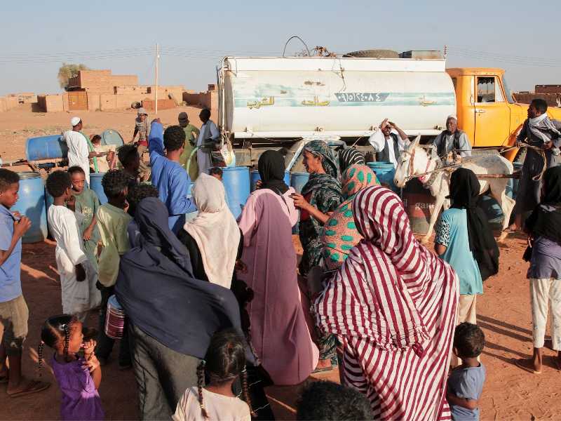 Persone riempiono i contenitori d'acqua a un punto di distribuzione gratuito. Foto LaPresse