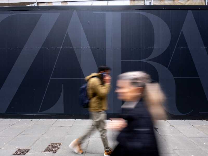 A passeggio per Oxford Street a Londra davanti a un logo di grandi dimensioni di Zara (Mike Kemp/In Pictures via Getty Images)
