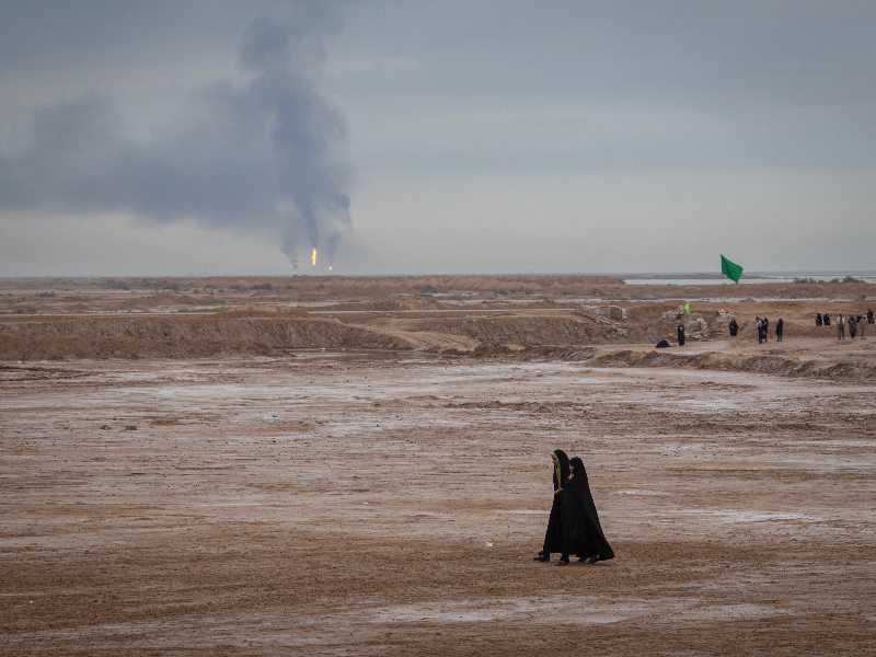 Due donne iraniane velate, sullo sfondo dei pozzi petroliferi di Shalamcheh, città iraniana vicino al confine con l'Iraq (Morteza Nikoubazl/NurPhoto via Getty Images)