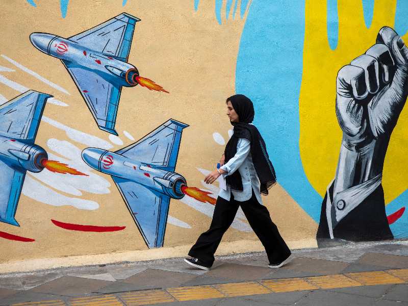 Passanti davanti a un murale politico filo-governativo il 12 aprile 2026 a Teheran (Getty)